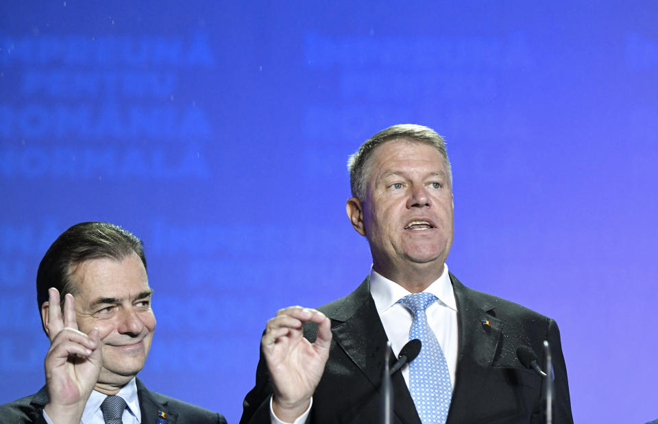 Romanian President Klaus Iohannis, right, speaks next to Romanian Prime Minister Ludovic Orban, after exit polls results indicate him as the leader of the presidential race, with up to 40 percent of the votes in Bucharest, Romania, Sunday, Nov. 10, 2019. An election runoff will take place on Nov. 24. (AP Photo/Andreea Alexandru)