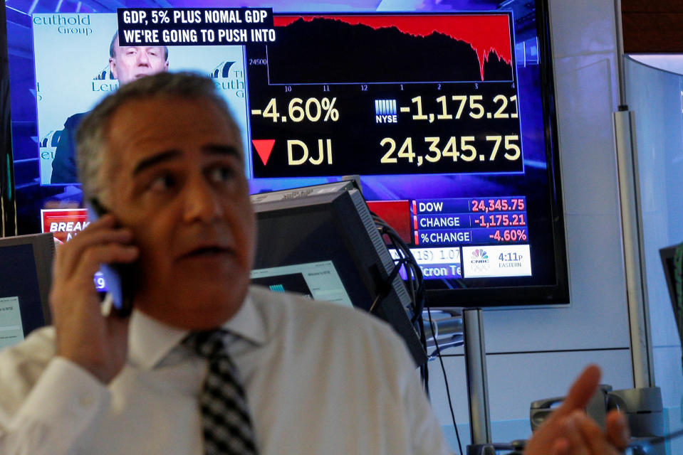 A trader works on the floor following the closing bell as a screen shows the Dow Jones Industrial Average on the New York Stock Exchange, (NYSE) in New York, U.S., February 5, 2018. REUTERS/Brendan McDermid