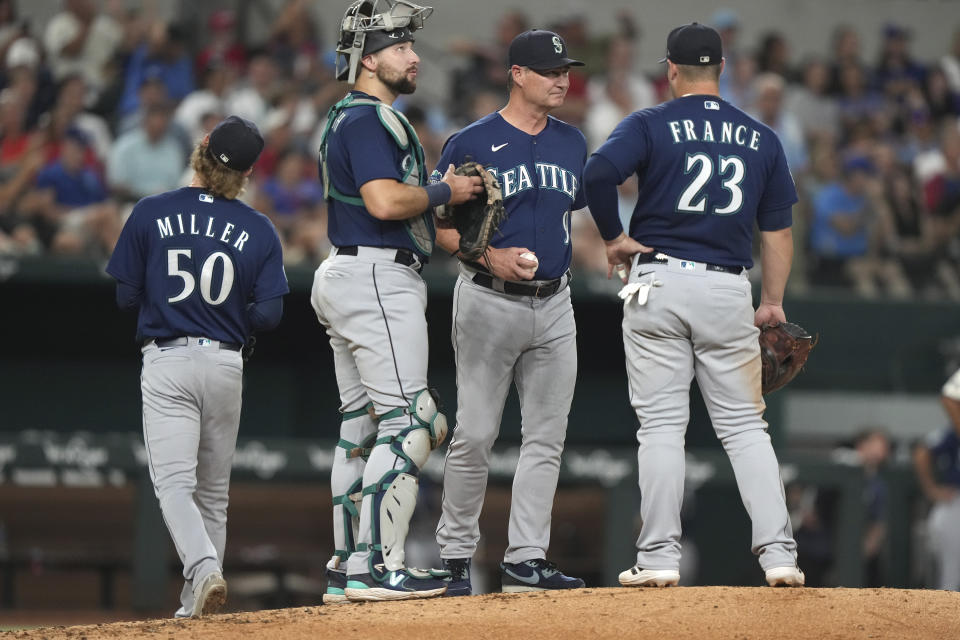 Seattle Mariners manager Scott Servais (9) stands on the mound with first baseman Ty France (23) and catcher Cal Raleigh (29) as starting pitcher Bryce Miller (50) leaves during the fifth inning of the team's baseball game against the Texas Rangers in Arlington, Texas, Friday, Sept. 22, 2023. (AP Photo/LM Otero)