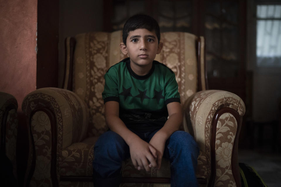 In this Sept. 17, 2018, photo, 8-year-old Mohamed al-Dalo sits in his living room as he waits for breakfast before going to school in Gaza City. Ever since Hamas launched demonstrations in March against Israel's blockade of Gaza, children have been a constant presence in the crowds. Since then, U.N. figures show that 948 children under 18 have been shot by Israeli forces and 2,295 have been hospitalized, including 17 who have had a limb amputated. (AP Photo/Felipe Dana)