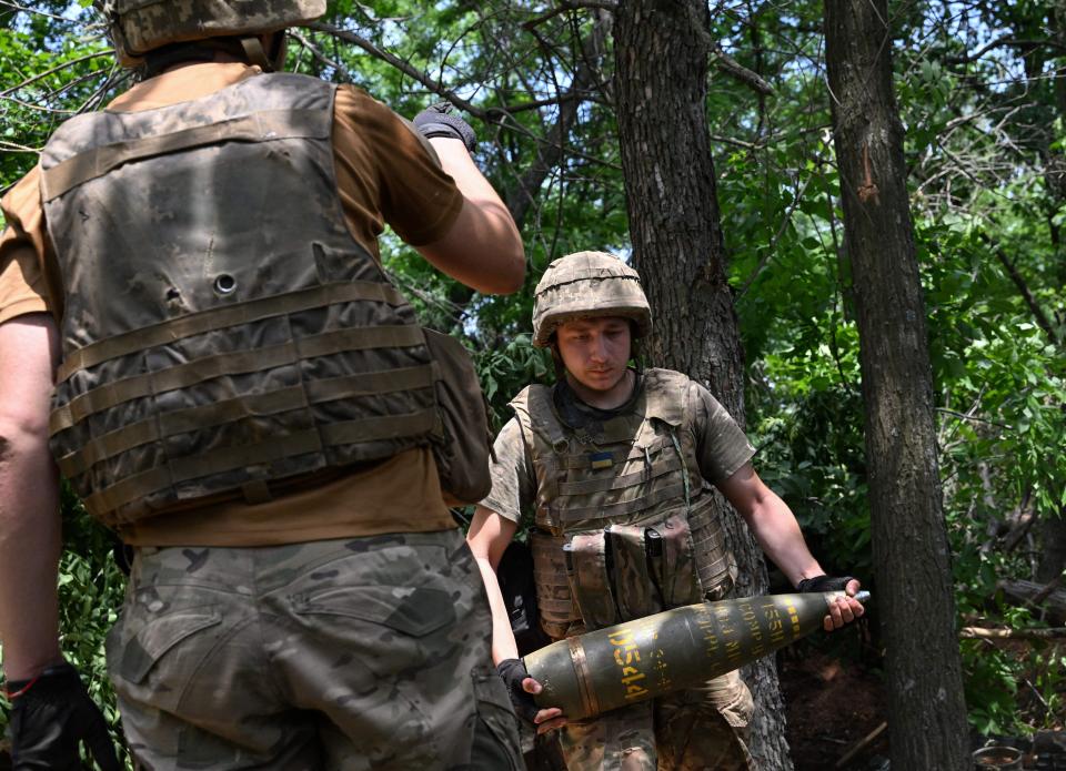 A Ukrainian artilleryman carries a 155 mm shell to fire a M777 howitzer toward Russian positions near Avdiivka in the Donetsk region on June 23, 2023.