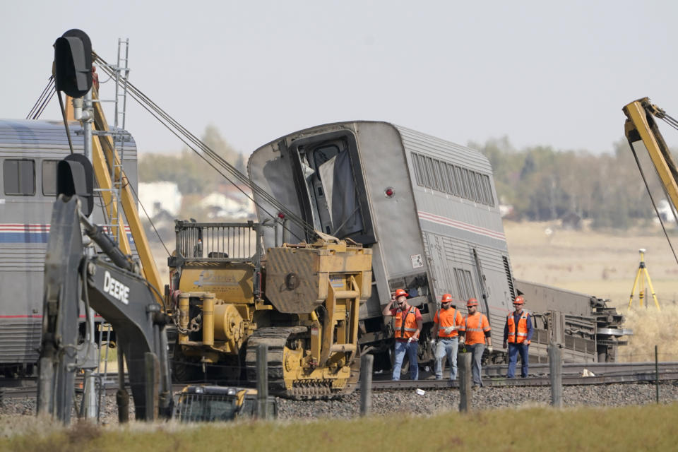 Workers walk Sunday, Sept. 26, 2021, next to an Amtrak train that derailed Saturday just west of Joplin, Mont. The westbound Empire Builder was en route to Seattle from Chicago, with two locomotives and 10 cars. (AP Photo/Ted S. Warren)