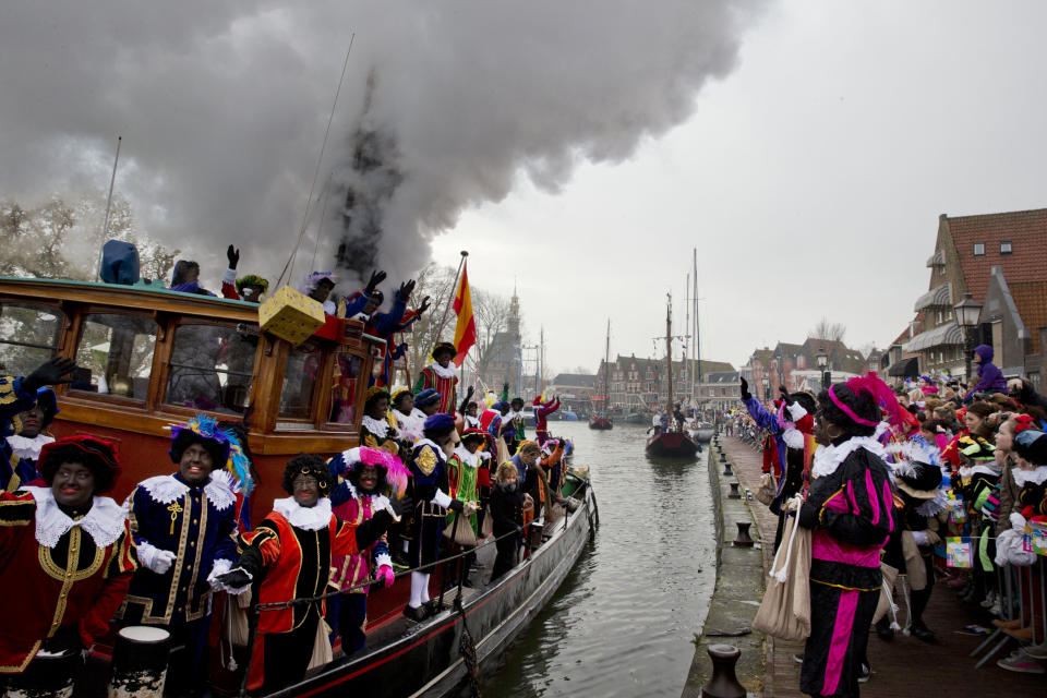 In this Saturday Nov. 16, 2013, file photo, people dressed as "Zwarte Piet" or "Black Pete", wave to spectators as they arrive with the Sinterklaas, the Dutch version of Santa Claus, by steamboat in Hoorn, north-western Netherlands. As many Dutch children eagerly anticipate the arrival of their country's version of Santa Claus this weekend, opponents and supporters of his controversial helper Black Pete are gearing up for protests. Black Pete is often played by white people with their faces daubed in dark makeup. Supporters see him as a traditional children's character, while opponents decry him as a racist stereotype. (AP Photo/Peter Dejong)