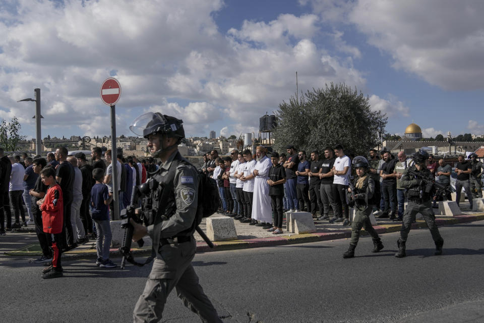 FILE - Palestinian Muslim worshipers who were prevented from entering the Al-Aqsa Mosque pray outside Jerusalem's Old City as Israeli forces stand guard on Nov. 17, 2023. ore than 270 Palestinian citizens have been arrested in a crackdown on free speech and political activity since the Hamas attack, according to Adalah, an advocacy organization for Palestinians inside Israel. Palestinian citizens have also reported intimidation, firings and expulsions from universities, as well as surveillance of their online speech. (AP Photo/Mahmoud Illean, File)