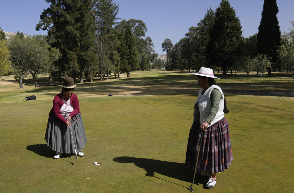 Aymara Indigenous women, Teresa Zarate, left, putts the ball while Martha Mamani watches her during the workers' tournament at the La Paz Golf Club of Mallasilla on the outskirts of La Paz, Bolivia, Monday, Aug. 1, 2022. (AP Photo/Juan Karita)