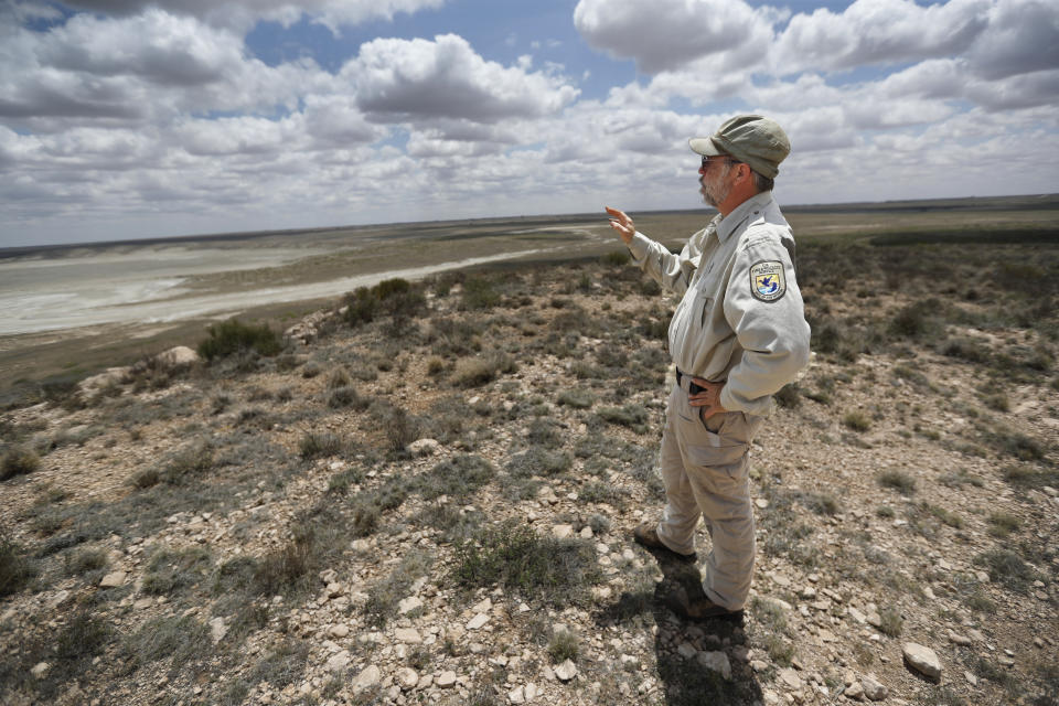 Biologist Jude Smith stands on a bluff overlooking an empty saline lake at the Muleshoe National Wildlife Refuge outside Muleshoe, Tex., on Tuesday, May 18, 2021. The lake is fed by the Ogallala Aquifer, which has been become increasingly dry because of irrigation and drought. (AP Photo/Mark Rogers)