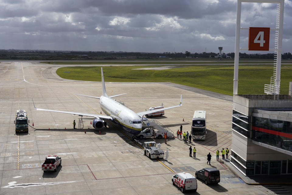 A bus with passengers who disembarked from the Australian cruise ship "Greg Mortimer" arrives on the tarmac at the international airport in Montevideo, Uruguay, Wednesday, April 15, 2020. The ship has been anchored off Uruguay's coast since March 27 with more than half its passengers and crew infected with the new coronavirus, according to authorities. (AP Photo/Matilde Campodonico)