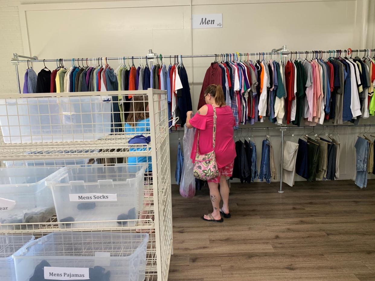 A mother and her daughter shop for free clothing for a loved one at Love and Care Ministries on March 13, 2024, amidst empty boxes in the men's section in need of donations.