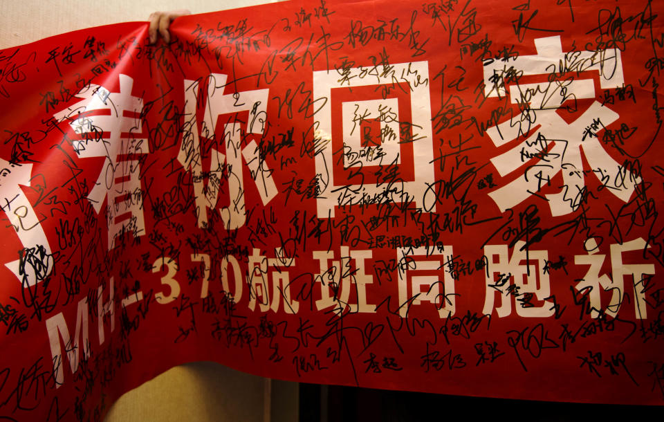 A Chinese university student displays a banner that reads: "We hope your return, compatriots of Flight MH370" with signatures of other students at a hotel for relatives or friends of passengers aboard the missing Malaysian Airlines plane in Beijing Monday, March 10, 2014. The anguished hours had turned into a day and a half. Fed up with awaiting word on the missing plane, relatives of passengers in Beijing lashed out at the carrier with a handwritten ultimatum and an impromptu news conference. (AP Photo/Andy Wong)