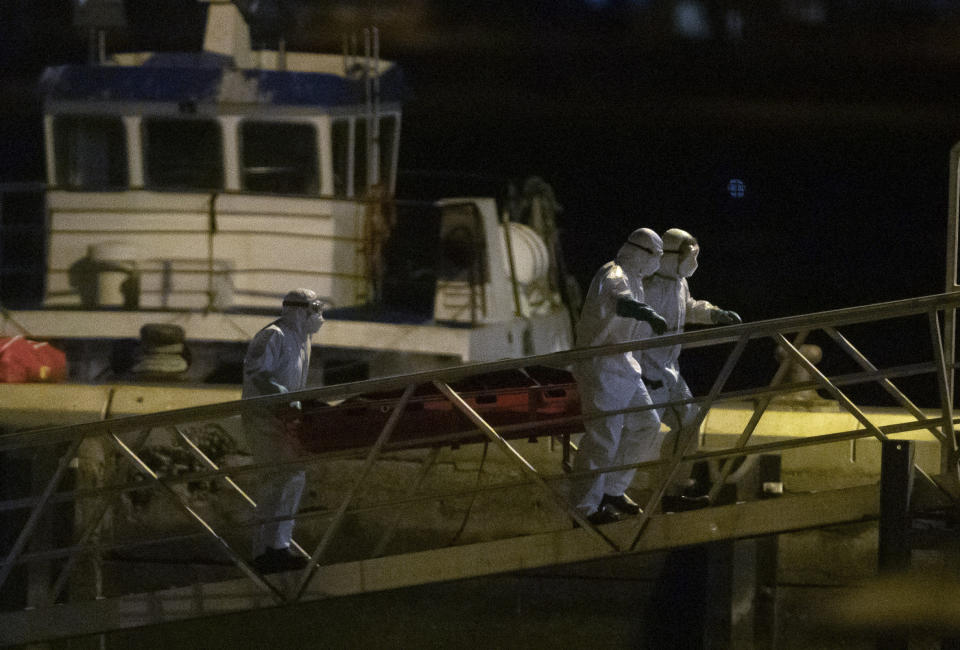 Emergency services carry dead bodies of migrants after being recovered from a wooden boat at the port of Los Cristianos in the south of Tenerife, in the Canary Island, Spain, Wednesday, April 28, 2021. Spanish authorities have brought to shore the bodies of 24 migrants from sub-Saharan Africa, among them two minors. The migrant boat was spotted on Monday by a Spanish military plane 265 nautical miles from the island of El Hierro, three survivors were airlifted, the others are believed to have died from thirst and hunger during the perilous migratory journey from the West coast of Africa to the Canary Islands. (AP Photo/Andres Gutierrez)