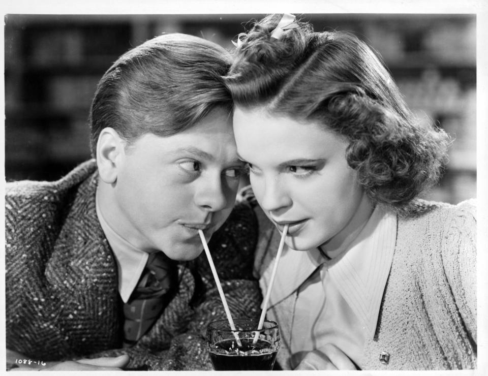 Mickey Rooney and Judy Garland sharing a soda together as they stare into one an others eyes in a scene from the film 'Babes In Arms'