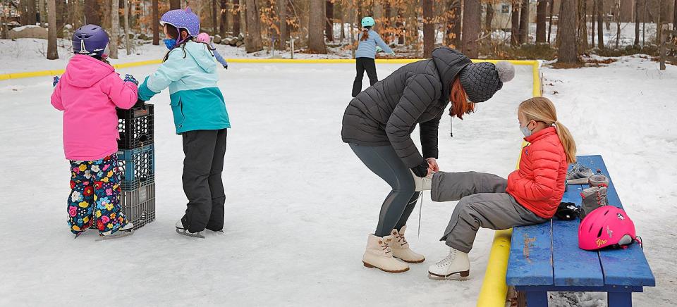 Mom Jackie Sousa helps lace up skates on daughter Lexi, 8, at the Norwell Skating Rink on Pine Street Monday Feb. 15, 2021.