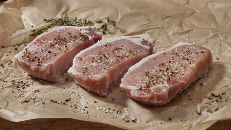 pork chops with salt and pepper on cutting paper