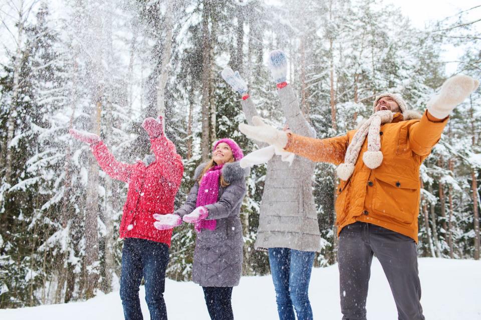 group of smiling men and women in winter forest