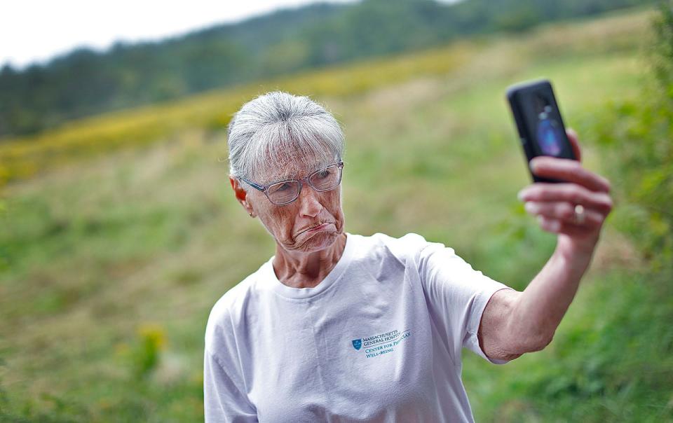Mary Harris, 71, of Whitman, who has "been coming since as long as I can remember," takes a sad-faced selfie photo of the farm pasture which she is afraid would become more developments. Peaceful Meadows in Whitman was up for auction on Tuesday, Aug. 29, 2023.