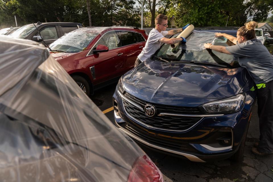 Todd Wenzel Buick GMC Of Davison employees work on covering glass from cars damaged by baseball-sized hail that came through Davison during a storm that moved through Michigan on Thursday, July 20, 2023.