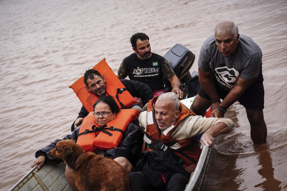 People evacuate an area flooded by heavy rains, in Porto Alegre, Rio Grande do Sul state, Brazil, Friday, May 3, 2024. (AP Photo/Carlos Macedo)