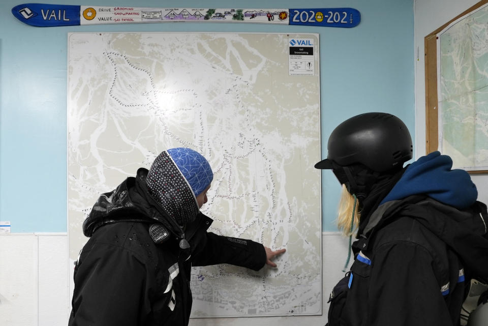 CORRECTS LAST NAME TO SCHIFANI FROM SHIFANI - Snowmakers Kate Schifani, left, and Ryan Schultz review a snowmaking map at Vail Mountain, Wednesday, Dec. 29, 2021, in Vail, Colo. Newer snowmaking technology is allowing ski areas to be more efficient with energy and water usage as climate change continues to threaten snowpack levels. (AP Photo/Brittany Peterson).