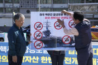 Protesters put stickers on a banner during a rally to oppose the planned the joint military exercises between the U.S. and South Korea in front of the U.S. Embassy in Seoul, South Korea, Thursday, Sept. 22, 2022. The nuclear-powered aircraft carrier USS Ronald Reagan arrived in the South Korean port of Busan on Friday ahead of the two countries' joint military exercise that aims to show their strength against growing North Korean threats. The signs read: "Refusal for peace on the Korean Peninsula." (AP Photo/Ahn Young-joon)