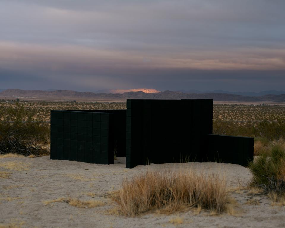 Made of cinder block, the structures read as stark ruins or abandoned construction projects. There are ten such structures scattered across 11 acres of open desert.