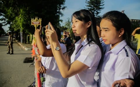 Onlookers watch and cheer as a helicopter flies towards an airstrip near Tham Luang Nang Non cave - Credit: Lauren DeCicca 