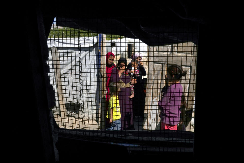 Syrian women and their children, seen through a tent window, stand at a refugee camp in the town of Bar Elias, in Lebanon's Bekaa Valley, Tuesday, June 13, 2023. Aid agencies are yet again struggling to draw the world's attention back to Syria in a two-day donor conference hosted by the European Union in Brussels for humanitarian aid to Syrians that begins Wednesday. Funding from the conference also goes toward providing aid to some 5.7 million Syrian refugees living in neighboring countries, particularly Turkey, Lebanon and Jordan. (AP Photo/Bilal Hussein)