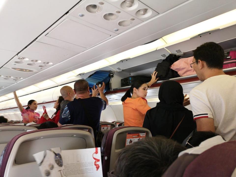 Passengers load luggage into overhead bins