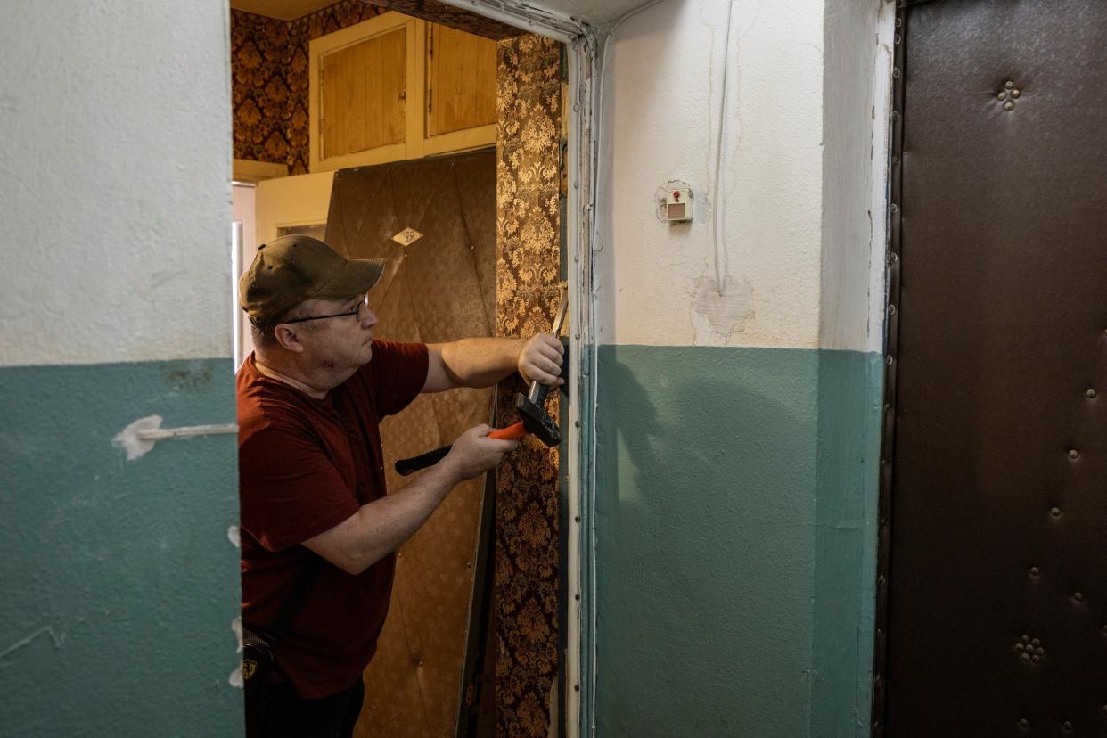 A Kyiv resident dismantles a door that was destroyed during Russian missile strikes (REUTERS)