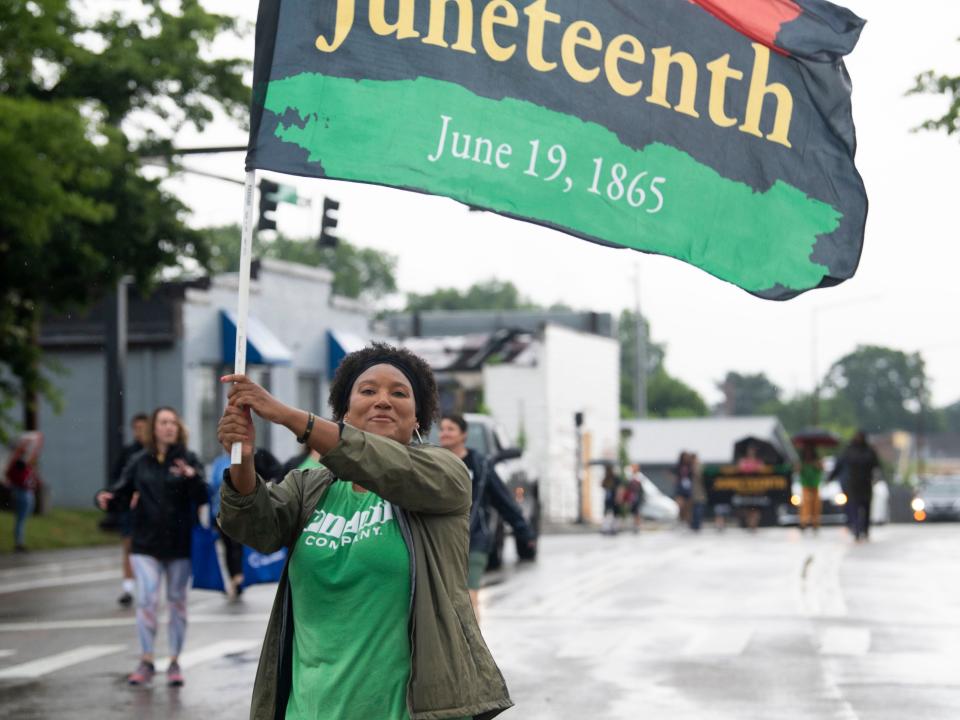 A woman carries a Juneteenth flag along Martin Luther King Jr. Boulevard during the MLK Memorial Parade and Juneteenth Celebration on June 19.
