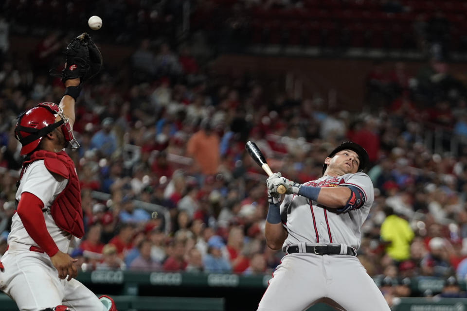 St. Louis Cardinals catcher Willson Contreras, left, reaches for a ball as Atlanta Braves' Austin Riley bends out of the way during the seventh inning of a baseball game Monday, April 3, 2023, in St. Louis. (AP Photo/Jeff Roberson)