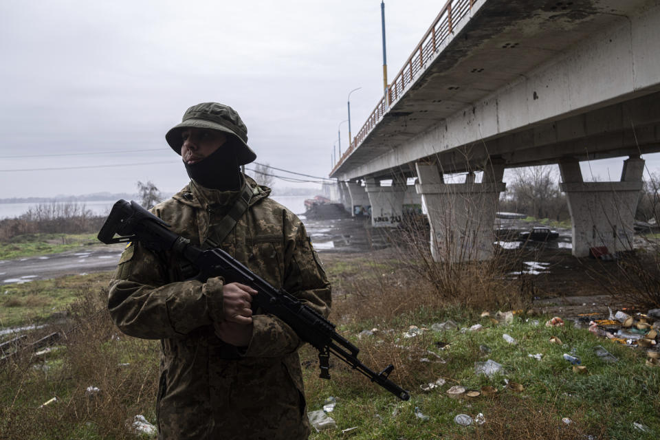 A Ukrainian serviceman patrols area near the Antonovsky Bridge which was destroyed by Russian forces after withdrawing from Kherson, Ukraine, Thursday, Dec. 8, 2022. (AP Photo/Evgeniy Maloletka)