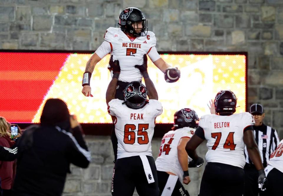 N.C. State offensive lineman Jacarrius Peak (65) lifts quarterback Brennan Armstrong (5) up after Armstrong scored on a one-yard touchdown run during the second half of N.C. State’s 35-28 victory over Virginia Tech at Lane Stadium in Blacksburg, VA, Saturday, Nov. 18, 2023.