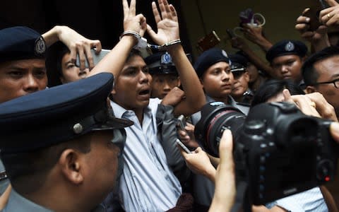 Burmese journalist Kyaw Soe Oo is escorted by police after being sentenced by a court to jail in Yangon - Credit: AFP