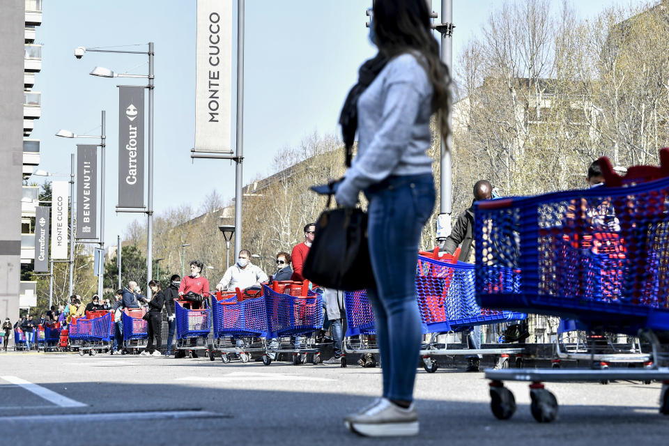 People queue waiting to enter a supermarket in Turin, Italy, Saturday, March 21, 2020. For most people, the new coronavirus causes only mild or moderate symptoms. For some it can cause more severe illness. (Marco Alpozzi/LaPresse via AP)