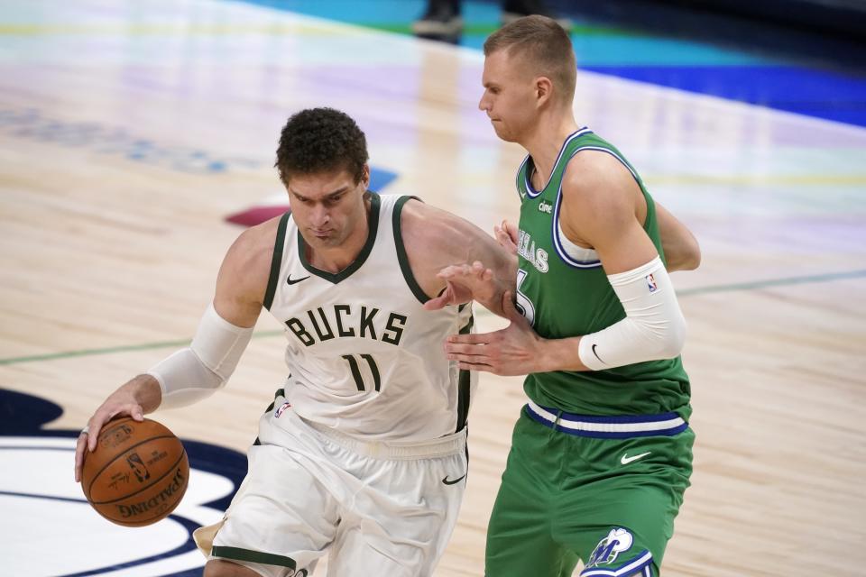 Milwaukee Bucks center Brook Lopez (11) works against Dallas Mavericks center Kristaps Porzingis, right, in the first half of an NBA basketball game in Dallas, Thursday, April 8, 2021. (AP Photo/Tony Gutierrez)