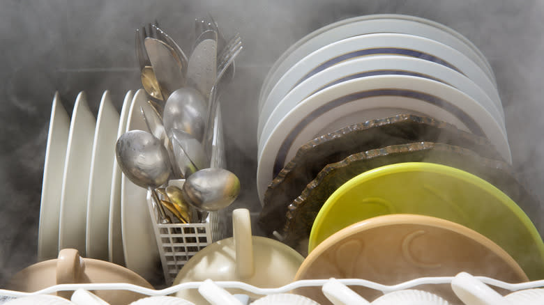 Dishes and silverware arranged in a steamy dishwasher