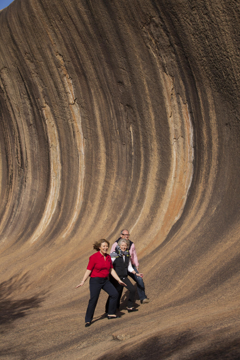 Three travellers pose at Wave Rock in Margaret River, Western Australia.