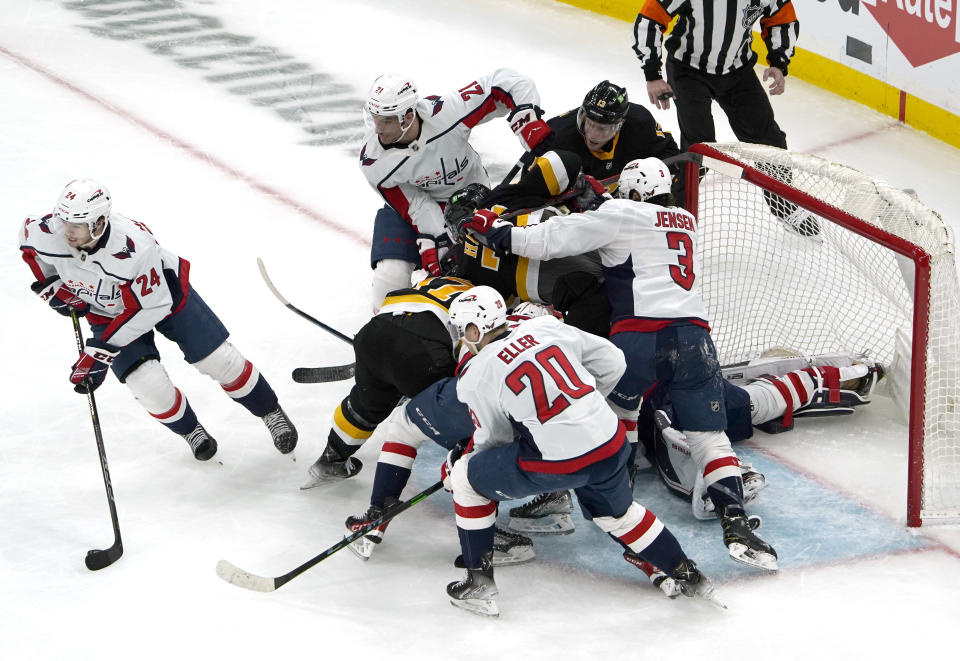 Washington Capitals center Connor McMichael (24) carries the puck away from a pile of his teammates and Boston Bruins players in front of the net during the first period of an NHL hockey game, Thursday, Jan. 20, 2022, in Boston. (AP Photo/Mary Schwalm)