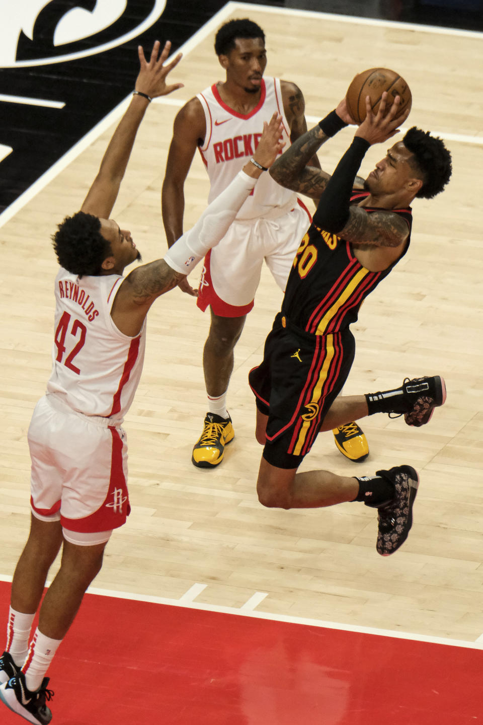 Houston Rockets forward Cameron Reynolds (42) tries to block Atlanta Hawks forward John Collins (20) during the first half of an NBA basketball game on Sunday, May 16, 2021, in Atlanta. (AP Photo/Ben Gray)