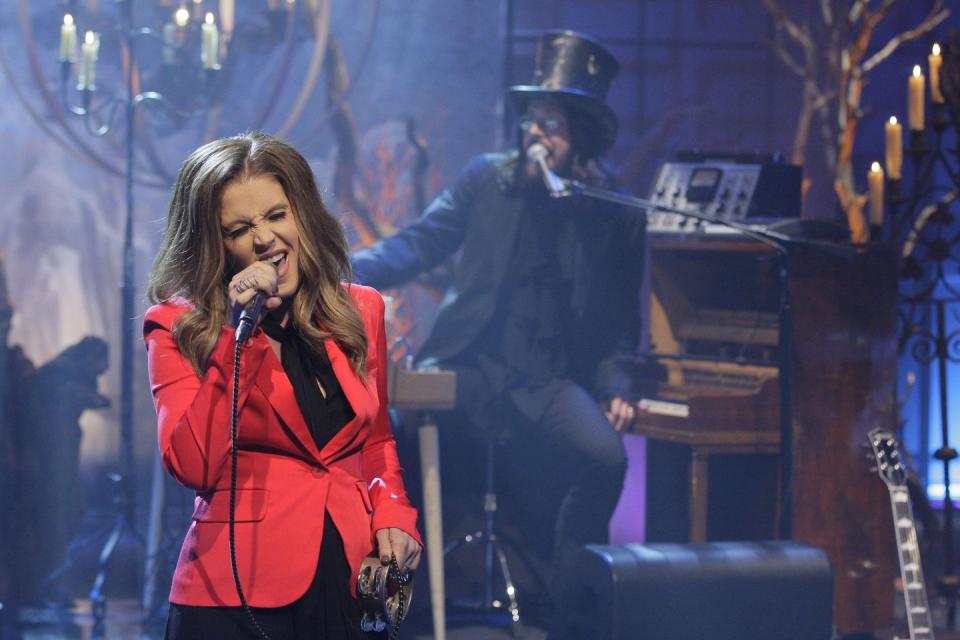 lisa marie presley performing in a red suit and singing into a microphone