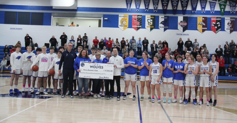 Members of the Perry Booster Club and Perry boys and girls basketball teams pose for a photo during a check presentation from the Iowa Wolves as part of a doubleheader against Greene County on Tuesday, Feb. 6, 2024, at Perry High School.