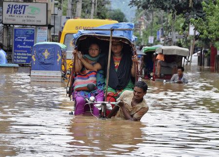 People use cycle rickshaws to commute through a flooded road after heavy rains in the northeastern Indian city of Guwahati September 23, 2014. REUTERS/Utpal Baruah