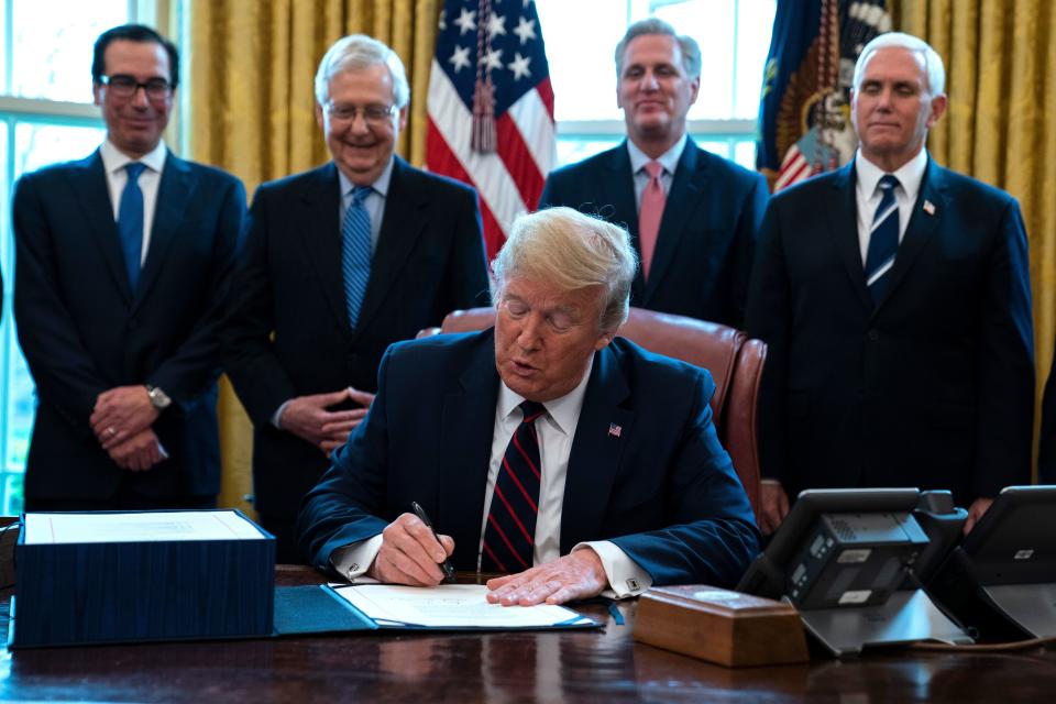 President Donald Trump signed the $2 trillion coronavirus stimulus relief package in the Oval Office at the White House on Friday. (ASSOCIATED PRESS)