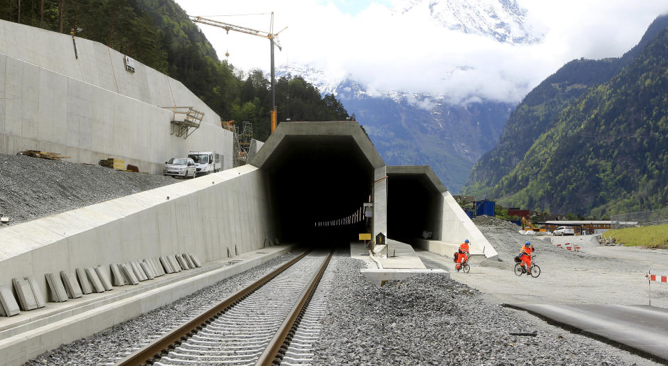 Workers cycle past the northern entrances of the NEAT Gotthard Base tunnel near Erstfeld May 7, 2012. Crossing the Alps, the world's longest train tunnel should become operational at the end of 2016. The project consists of two parallel single track tunnels, each of a length of 57 km (35 miles)