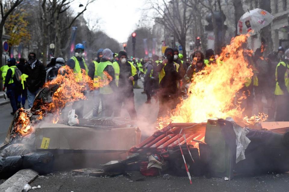 Protesters wearing yellow vests stand next to burning items near the Champ Elysees (AFP/Getty Images)