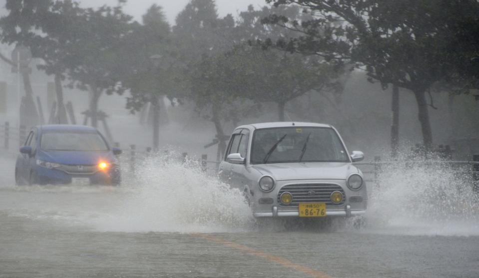 Cars drive on a waterlogged road due to heavy rain caused by approaching Typhoon Vongfong in Nishihara town on Japan's southern island of Okinawa, in this photo taken by Kyodo October 11, 2014. (REUTERS/Kyodo)