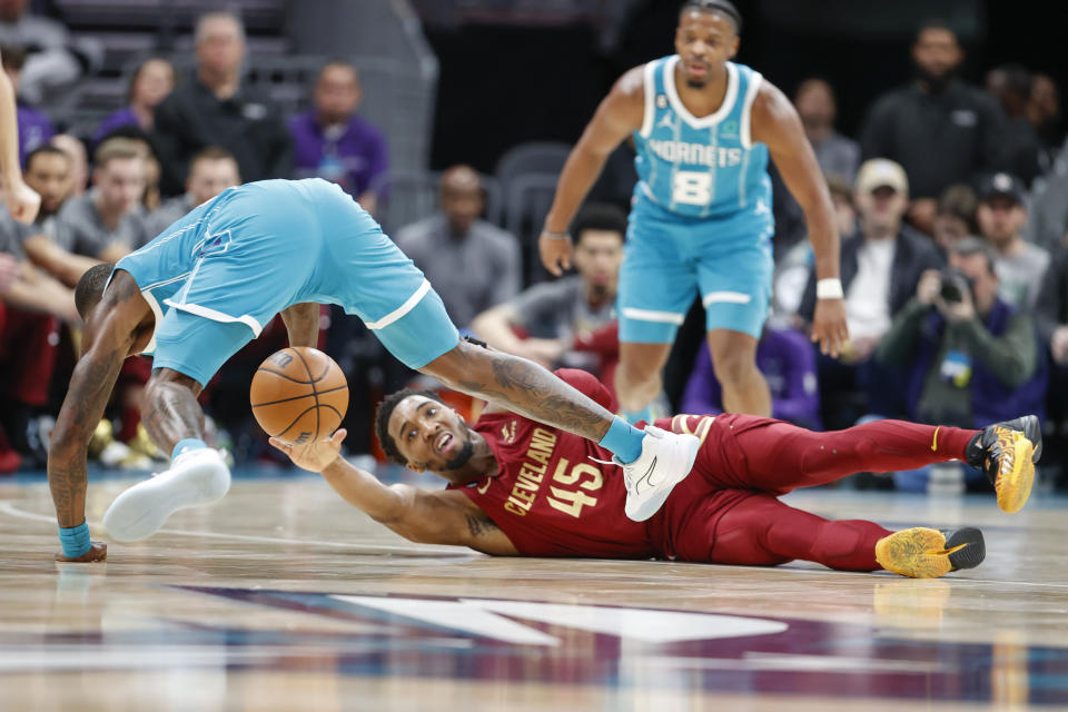 Cleveland Cavaliers guard Donovan Mitchell (45) and Charlotte Hornets guard Terry Rozier fight for a loose ball during the first half of an NBA basketball game in Charlotte, N.C., Sunday, March 12, 2023. (AP Photo/Nell Redmond)