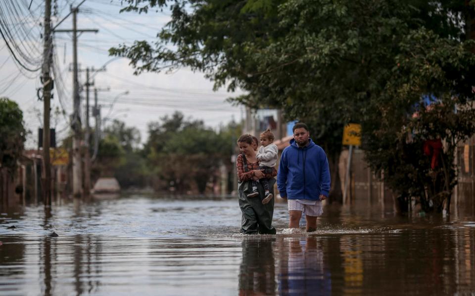 People walk through a flooded street in the Chacara neighborhood in Eldorado do Sul, Rio Grande do Sul state, Brazil