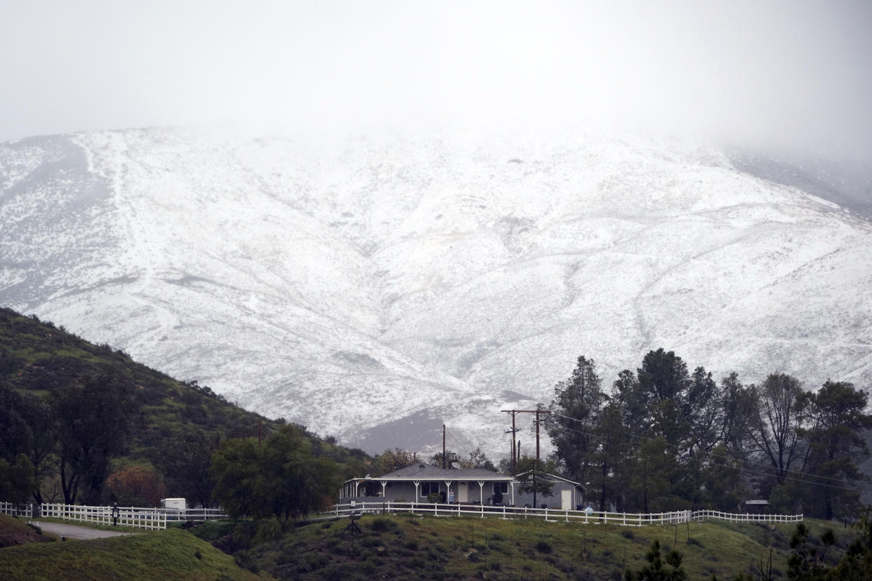 Snow accumulates on a hillside over a property Friday, Feb. 24, 2023, in Agua Dulce, Calif. California and other parts of the West faced heavy snow and rain Friday from the latest winter storm to pound the U.S. (AP Photo/Marcio Jose Sanchez)