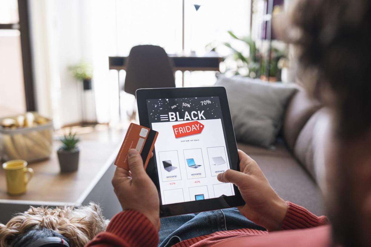 Man and her dog is relaxing at home and shopping electronics online during Black Friday sale.